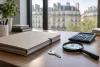 Un dossier patrimonial fermé, une clé, une loupe et une calculatrice éteinte devant des immeubles génériques